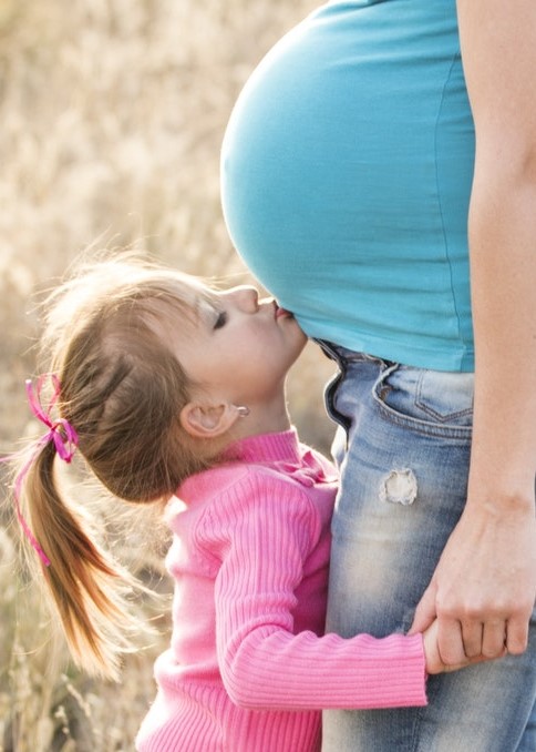 pregnant mom belly and little girl kissing it