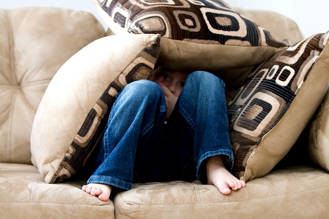 child hiding in couch